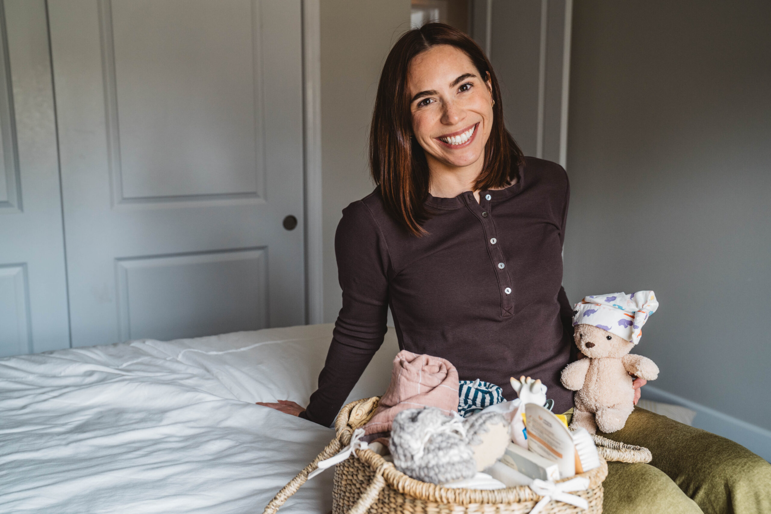 Smiling woman on bed with baby toys
