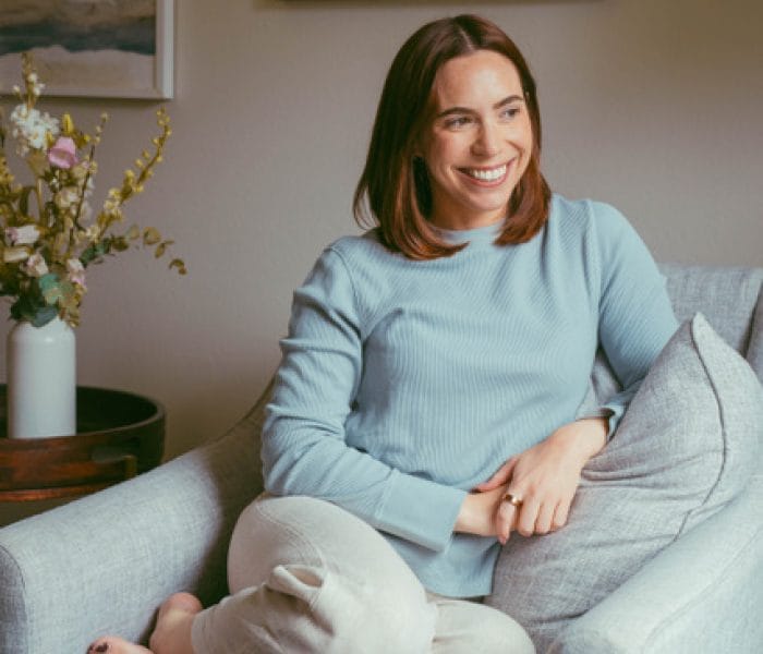 Olivia Calisano sitting on a couch smiling